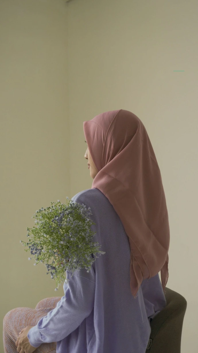 a woman sitting on a chair with a plant in her lap